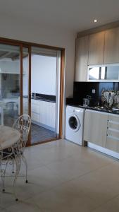a kitchen with a washing machine and a table and a dining room at Pérola do Oceano in Manta Rota