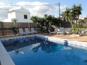 a swimming pool with chairs and a house at Pérola do Oceano in Manta Rota