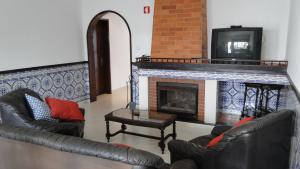 a living room with two leather chairs and a fireplace at Pérola do Oceano in Manta Rota