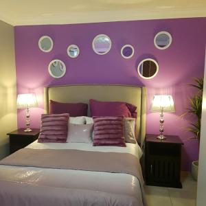 um quarto com paredes roxas e uma cama com almofadas em Dinaledi House em Bela-Bela