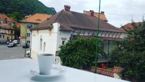 eine Tasse Kaffee auf einem Tisch vor einem Haus in der Unterkunft Apart City Center in Braşov