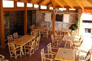 a restaurant with wooden tables and chairs and a stone wall at Pansion Baša in Ustikolina