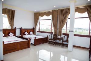 a bedroom with two beds and two windows at Hoa An Hotel in Rạch Giá