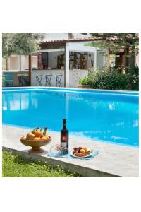 a bottle of wine and a bowl of fruit next to a swimming pool at Argo Apartments in Kato Daratso