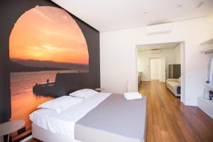 ein Schlafzimmer mit einem großen Bett mit einem Sonnenuntergangsbild an der Wand in der Unterkunft Cefalù Charme e Chic Suites in Cefalú