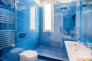 ein blaues Badezimmer mit Toilette, Badewanne und Waschbecken in der Unterkunft Cefalù Charme e Chic Suites in Cefalú + 40 Fotos