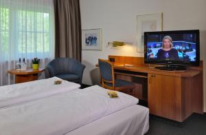 
a hotel room with a television and a bed at Hotel Sonnenhof - Garni in Pleinfeld

