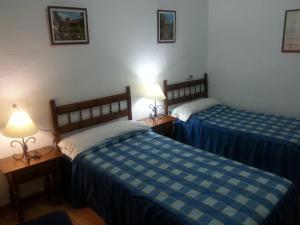 two beds in a hotel room with two lamps at Pensión Ciudad Navarro Ramos in Granada