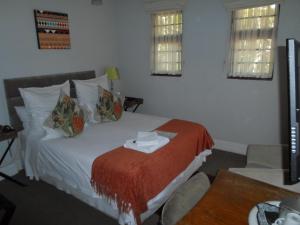 Melville Turret Guesthouse في جوهانسبرغ: غرفة نوم بسرير وبطانية حمراء