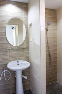 Un baño con lavabo y ducha con espejo. en Field Town Apartment, en Nakhon Nayok