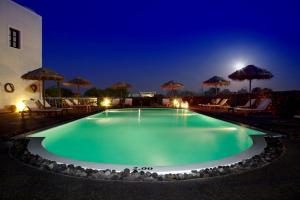 a swimming pool at night with chairs and umbrellas at Anna Traditional Apartments in Kamari
