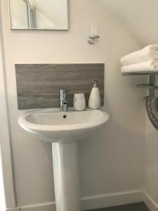 ein weißes Waschbecken im Bad mit einem Spiegel und Handtüchern in der Unterkunft Daedalus Bed & Breakfast in Muir of Ord