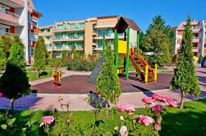 a playground in front of a building with pink flowers at GT Sunny Fort Apartments in Sunny Beach