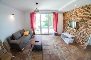 a living room with a couch and a brick wall at SOWI KĄT domki i apartamenty in Mikołajki