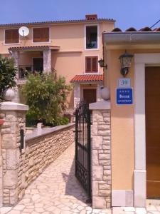a house with a gate with a sign on it at Sea view apartmant Nona with pool in Ližnjan