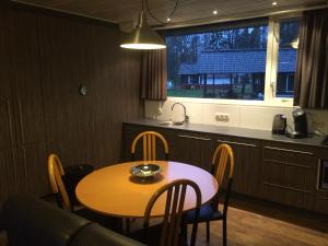 einen Tisch und Stühle in einer Küche mit einem Tisch und einem Fenster in der Unterkunft Vosseven 32 Geelgors in Stramproy
