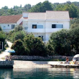 una casa con persone sedute sulla riva di uno specchio d'acqua di Apartments Roko a Mali Iž