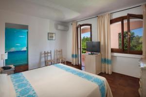1 dormitorio con 1 cama, TV y ventanas en Hotel Capriccioli en Porto Cervo
