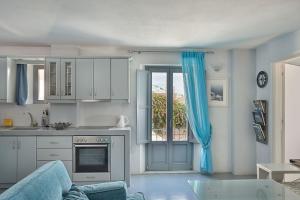 a kitchen with white cabinets and a blue curtain at Villa Dakoronia in Fira