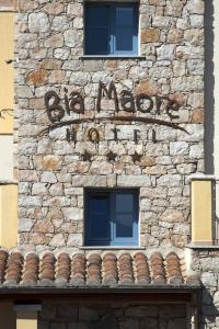 a stone building with a sign on it with two windows at Hotel Bia Maore in Baunei