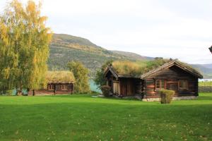 a log cabin with a grass roof on a green field at Sygard Storrvik in Storrvik