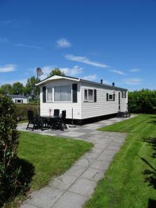 a mobile home with a patio and grass at Chalet de Boshoorn in Serooskerke