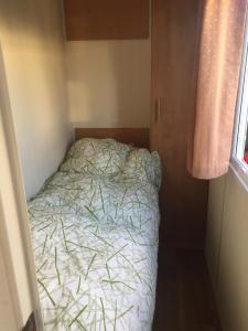 ein kleines Schlafzimmer mit einem Bett in einem kleinen Zimmer in der Unterkunft Stacaravan Jade in IJmuiden