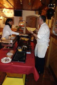a man and a woman in a kitchen preparing food at Hôtel du Chamois in L'Etivaz