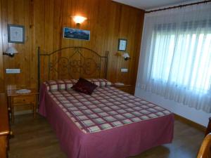 a bedroom with a bed with a purple comforter at Hotel Bellavista Ordesa in Torla-Ordesa