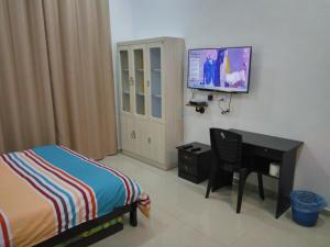 a bedroom with a bed and a desk and a tv at H2O Apartment in Cameron Highlands