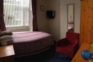 a bedroom with a bed and a chair and a window at Arkaig Guest House in Aberdeen