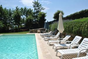 una fila de tumbonas y una piscina con sombrilla en A Casa di Giulia, en Siena