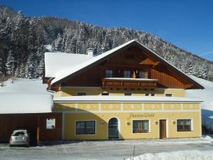 a building with a snow covered mountain in the background at Pension Wald in Faistenau