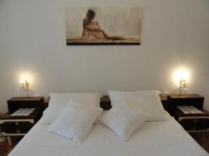 1 cama con almohadas blancas y una pintura en la pared en Dada Apartment, en Rijeka 18 fotos más
