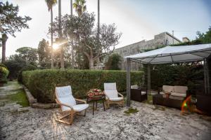 a patio with two chairs and a table and an umbrella at Villa De Pietro in Cursi