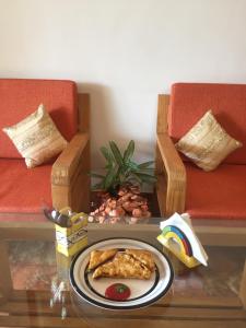 a table with a plate of pizza and two chairs at Villa Baywalk Goa - 200 meters from Morjim Beach in Morjim