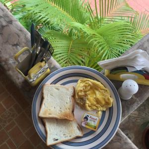 a plate of food with toast and eggs on it at Villa Baywalk Goa - 200 meters from Morjim Beach in Morjim