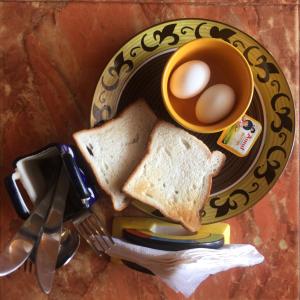 a plate with toast and eggs and a cup of coffee at Villa Baywalk Goa - 200 meters from Morjim Beach in Morjim