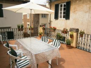 ルッカにあるPietrarosa Apartmentのテーブルと椅子、バルコニー(パラソル付)