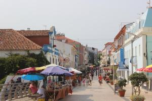 uma rua com guarda-chuvas e pessoas andando por uma rua em Casa do Sul na Ericeira