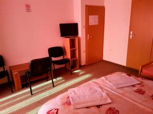 a bedroom with a bed and chairs and a tv at Hostel Imran Zenica in Zenica +40 photos