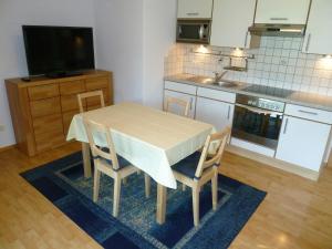 eine Küche mit einem Tisch und Stühlen sowie einem TV in der Unterkunft Ferienwohnung Sonnentraum in Hainzenberg