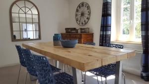 a dining room table with chairs and a clock on the wall at Mas des Mûriers in Saumane-de-Vaucluse