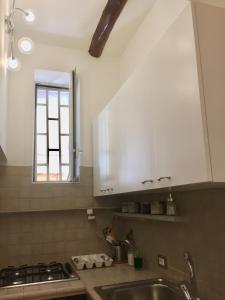 ナポリにあるNapoli Plebiscito Apartmentの白いキャビネット、シンク、窓付きのキッチン