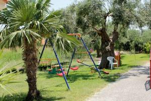 a playground in a park with two palm trees at Petradaki Apartments in Mola Kalyva