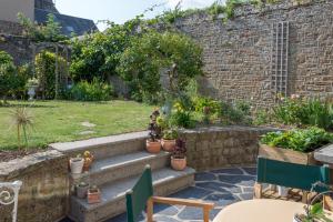 un jardin avec des plantes en pot et un mur en pierre dans l'établissement La Boudrie, à Avranches