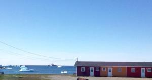 een rood gebouw naast een waterlichaam bij Oceanside Cabins in Bonavista