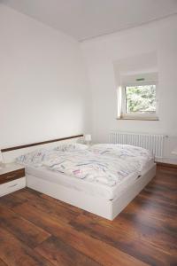 a white bed in a room with a wooden floor at Artus Hotel in Düsseldorf