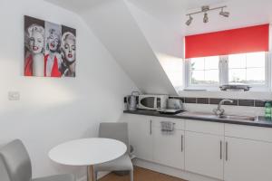 una pequeña cocina con armarios blancos y una mesa blanca en Park View Studio - Lydiard Millicent Swindon Wiltshire, en Swindon