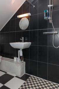 a bathroom with a sink and a black tiled wall at Park View Studio - Lydiard Millicent Swindon Wiltshire in Swindon